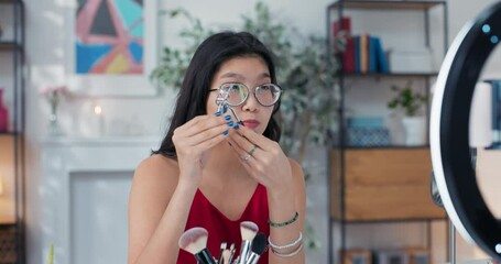 Beauty blogger shows off an eyelash curler to a live camera audience. A girl explains how to properly use makeup accessories. Influencer reveals the secret to beautiful lashes.