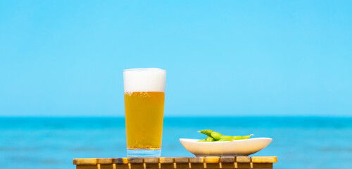 Fototapeta A glass of beer to drink on the beach. And Edamame.  ビーチで飲むビール。そして、おつまみの枝豆 obraz