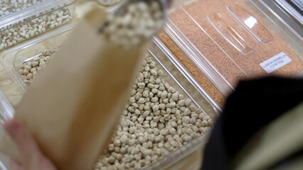 Shopkeeper filling glass jar with chickpeas