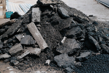 Pile of old black asphalt, road surface fragments outdoors