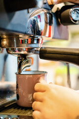 Close-up of a vintage mug in an espresso machine, with hot coffee coming out of the spout. vertical...