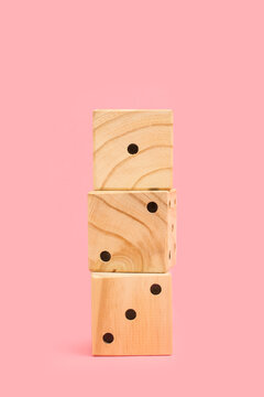 Tres dados apilados de madera sobre un fondo rosa liso y aislado. Vista de frente y de cerca. Copy space