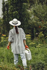 Women pours flowers in the garden with watering can