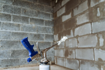 Construction gun emits spray foam, indoor construction, compressed air tool, steel foam tube.