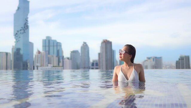 Sexy Female Model in Infinity Rooftop Pool With Amazing View of Modern Metropolis Buildings