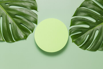 Round podium with jungle monstera leaves for summer product presentation, top view, flat lay