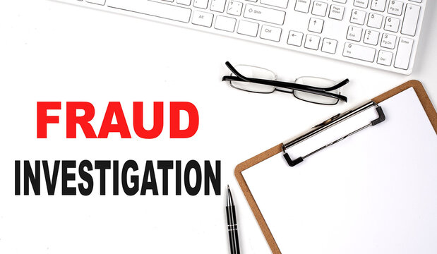FRAUD INVESTIGATION text written on the white background with keyboard, paper sheet and pen