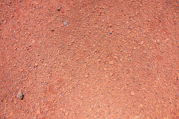 Textured background of clay soil and small orange stones