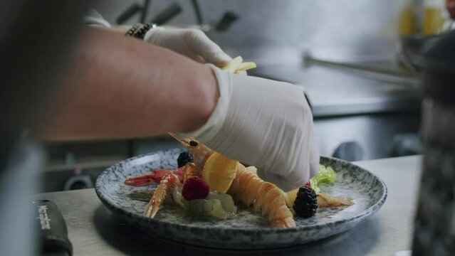 A professional Italian chef is preparing a tasty fish plate with scampi, salad and fruits - 01