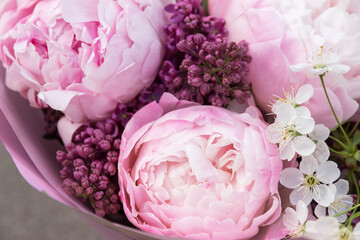 Beautiful spring bouquet of white pink peony, violet purple lilac and cherry flowers close-up, macro. Floral backdrop, background