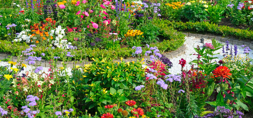 Colourful Flowerbeds and Winding Pathway in an Garden. Wide photo.