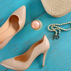 Ladies shoes, pearl necklace ,handbag and perfume on a blue background.
