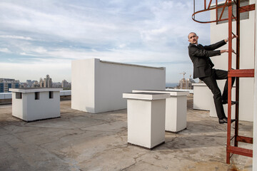 a man in a black suit with a tie hold on to the stairs to climb to new heights