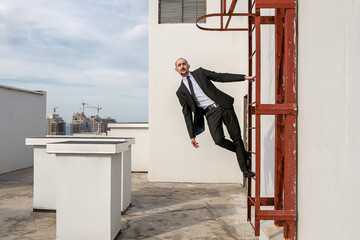a man in a black suit with a tie hold on to the stairs to climb to new heights