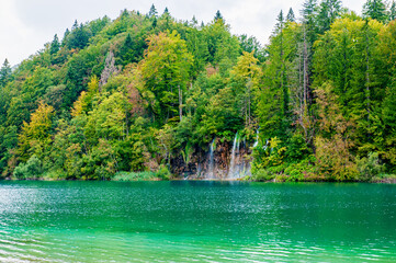 Waterfalls reflected in the lake. The magnificent landscape of the waterfall and lake. Majestic view of the Plitvice Lakes National Park