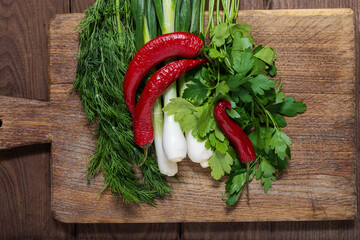 Red hot peppers and herbs on a wooden cutting board. Cooking. Flat lay.