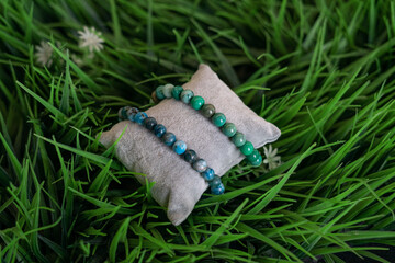 Two handmade bracelets, turquoise stones. On decorative green grass