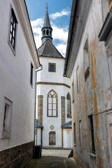 Fototapeta na wymiar A narrow street between old houses with view at the church, Czechia.