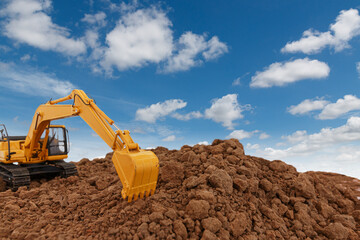 Selective focus with Bucket ,Excavator  are digging  soil in the construction site on sky  background,with white fluffy cloud