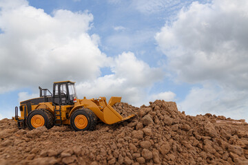 Wheel loader are digging the soil in the construction site on sky background ,with white fluffy cloud