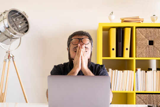 Tired businessman, young tired businessman rubbing his eyes. Confused, frustrated, sad or depressed young worker.