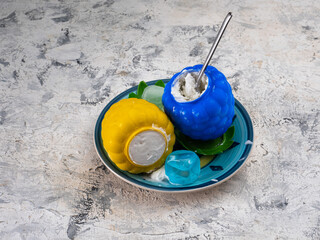 Ice cream with decorative cups of blue and yellow on a colored plate and a spoon