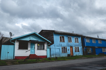 Fototapeta na wymiar Beautiful wooden houses with blue and sky-blue colors, and amazing cloudy sky, Valdivia, Chile