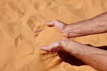 man holding coral pink sand in his hands