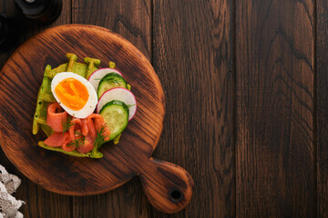 Savory waffles. Breakfast green waffles wild garlic or spinach with egg, tomato, salmon on wooden plate for breakfast on old dark wooden background. Light dinner, lunch or breakfast. Top view. Mock up