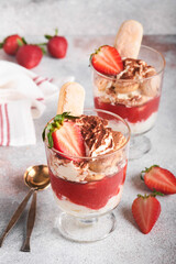 Strawberry tiramisu. Traditional Italian dessert tiramisu in glass with fresh strawberry and mint leaves on old gray concrete background table background. Copy space. Food background.