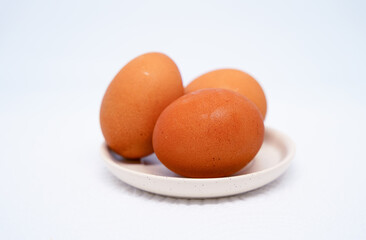 3 chicken eggs placed in a plate on a white background