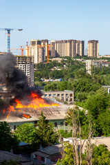 Old and new. An old abandoned building is burning against the background of new buildings