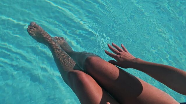 Slim tanned legs and feet of young female model in public pool in the spa.