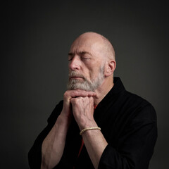 Naklejka premium Head and shoulders portrait of bald and bearded senior man with closed eyes contemplating, meditating or praying