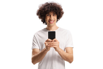 Cheerful casual young man with a dark curly hair using a smartphone and looking at camera