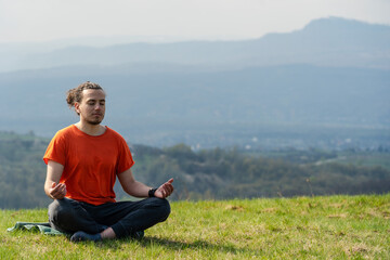 Naklejka na ściany i meble Young man do yoga on the rock peak. Meditation