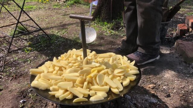 Sliced raw potatoes, roasted in large grill.