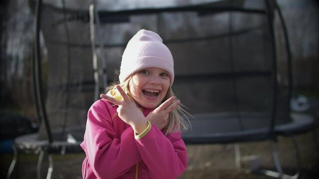 Playful Little Girl Smiling And Holding Up Peace Signs