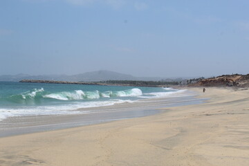 people walking along a beach with crashing waves