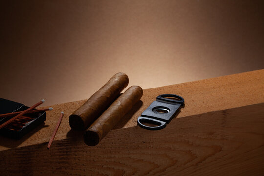 Two cigars and matches on the wooden beam.