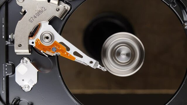 HDD spinning platter stops. Hard disk drive with moving read-write head turning off. High angle view