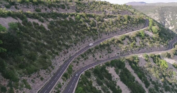 Aerial drone view of cars passing through curve roads on serpentines in France