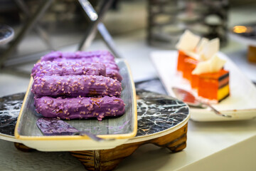 Eclairs with sweet purple topping with nuts on serving plate
