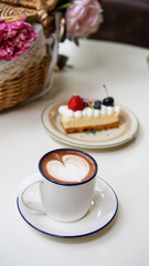 Latte art hot coffee with tulip milk latte art on top of white ceramic glass set on table in coffee shop Hot chocolate drink with white foam and cacao brown powder on top in short cup.