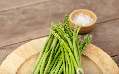 Asparagus is green and straight vegetable. Fresh, green asparagus is crispy for cook on wood table with salt