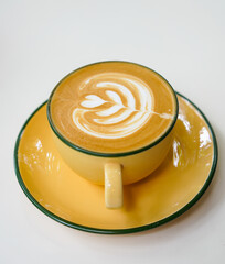 Latte art hot coffee with tulip milk latte art on top of white ceramic glass set on table in coffee shop Hot chocolate drink with white foam and cacao brown powder on top in short cup.