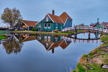 Fototapeta na wymiar April 13 2022, Zaanse Schans, Netherlands, Authentic wooden Dutch houses on the banks of the river Zaan. Reflections in the water.