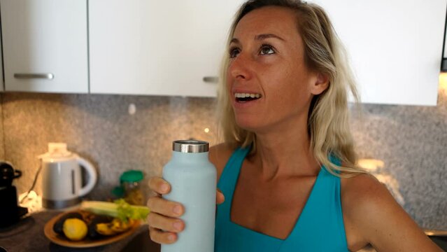 Fit Woman Drinking From Reusable Water Bottle In The Kitchen. Young Woman Drinking Water After Intense Workout