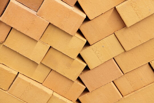 New yellow bricks diagonal stack close up. Brickwork building materials manufacturing storage and retail.