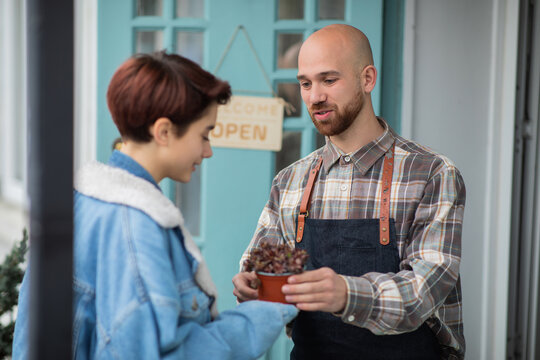 Modern and cute floral shop outside the shop the entrepreneur and owner of the shop have a discussion with the customer lady how to take care after the plants from the pot
